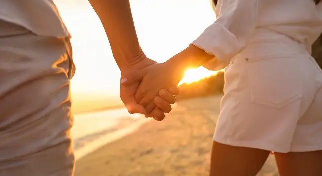 夕日の下で手を繋いでいる花嫁と花婿